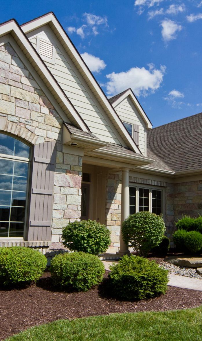 new house with stone facade and green bushes